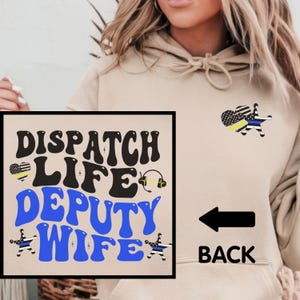 May include: A tan hoodie with the text "DISPATCH LIFE DEPUTY WIFE" in black and blue lettering with a thin blue line American flag and a sheriff's star on the front. The back of the hoodie has a thin blue line American flag and a sheriff's star with the word "BACK" printed below it.