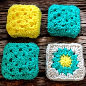 May include: Four crocheted squares in different colors and patterns. One square is yellow, one is turquoise, and two are white with a turquoise and yellow center.
