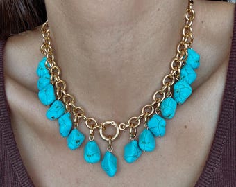 May include: A gold-toned chain necklace featuring turquoise-colored stone pendants. The necklace has a chunky chain design with a large clasp. The turquoise stones are irregularly shaped and add a pop of color to the jewelry.
