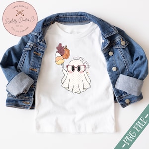 May include: A white t-shirt featuring a cute ghost wearing glasses and holding a bunch of autumnal items. The text "autumn girly" is written above the ghost.