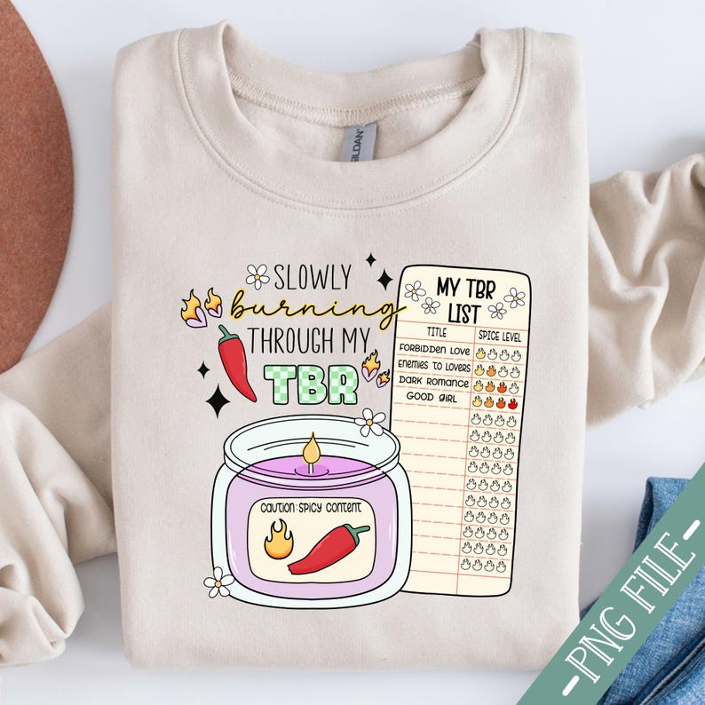 May include: A beige sweatshirt with a graphic of a candle with the text "Slowly burning through my TBR" and a checklist titled "My TBR List" with a spice level rating for different book genres.