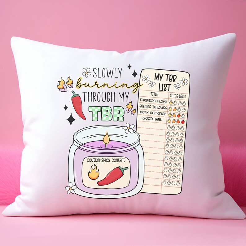 May include: White throw pillow with a graphic of a candle with a chili pepper and the text "Slowly burning through my TBR" and a list of book titles with a spice level rating.