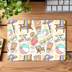 May include: A colourful beach-themed mouse mat with illustrations of beach chairs, sunglasses, beach balls, and a drink with a straw. The text "The beach is my happy place" is repeated on the mouse mat.