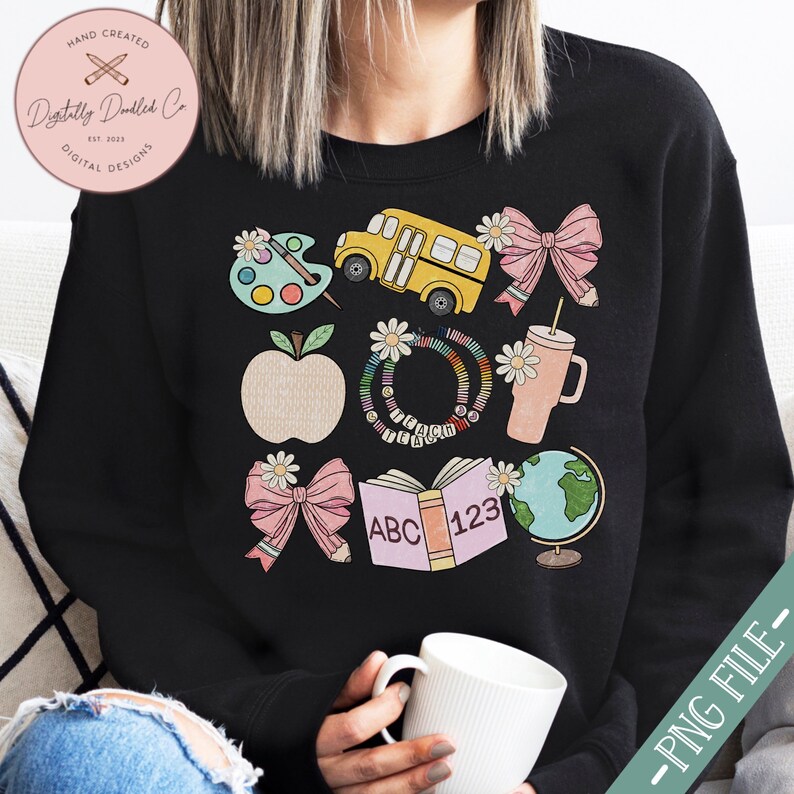 May include: Black sweatshirt with a colorful school-themed graphic. The design includes a yellow school bus, apple, books, globe, and bows. The text "HAND CREATED" and "Digitally Dindled Co" are visible. The words "ABC" and "123" are on a book.