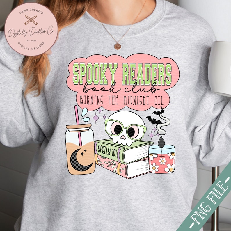 May include: A gray sweatshirt with a pink and green design that says "Spooky Readers Book Club Burning the Midnight Oil". The design includes a skull wearing glasses, a stack of books, a candle, and a glass of iced tea.