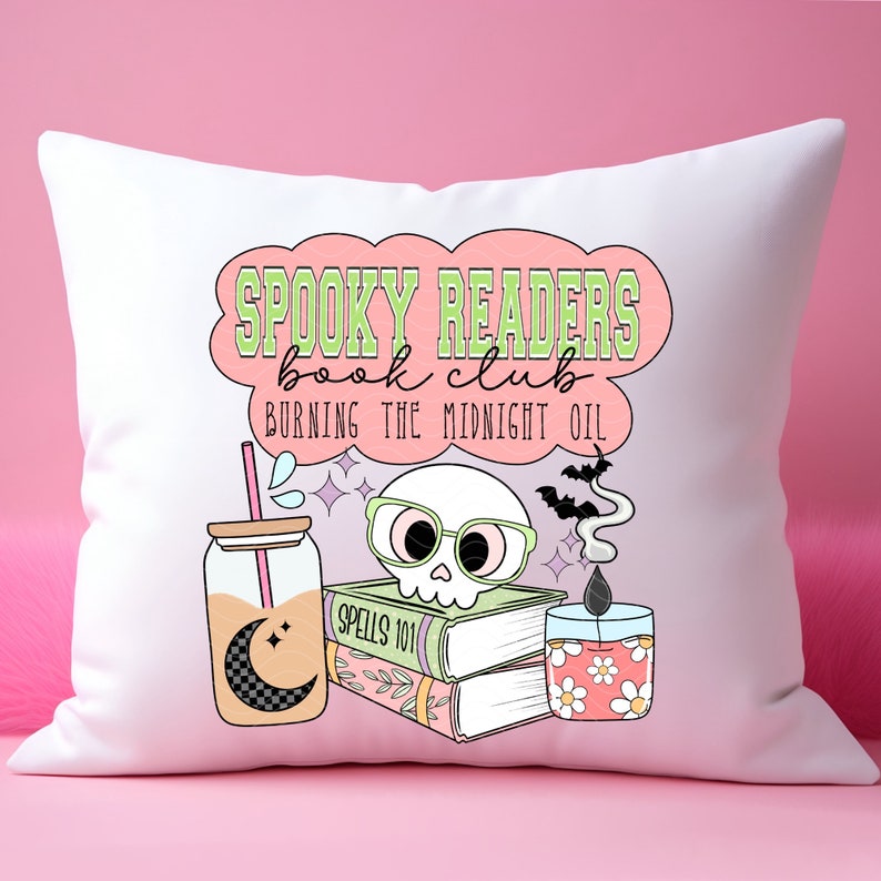 May include: White throw pillow with a pink and green design that says "Spooky Readers Book Club Burning the Midnight Oil". The design also includes a skull wearing glasses, a stack of books, a candle, and a glass jar with a straw.