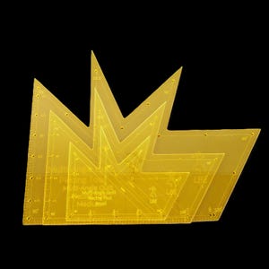 May include: A set of transparent yellow quilting tools with angled edges and measurement markings. The tools are layered, showing different sizes and angles, with text indicating their purpose as multi-angle quilt and precision piecing tools.