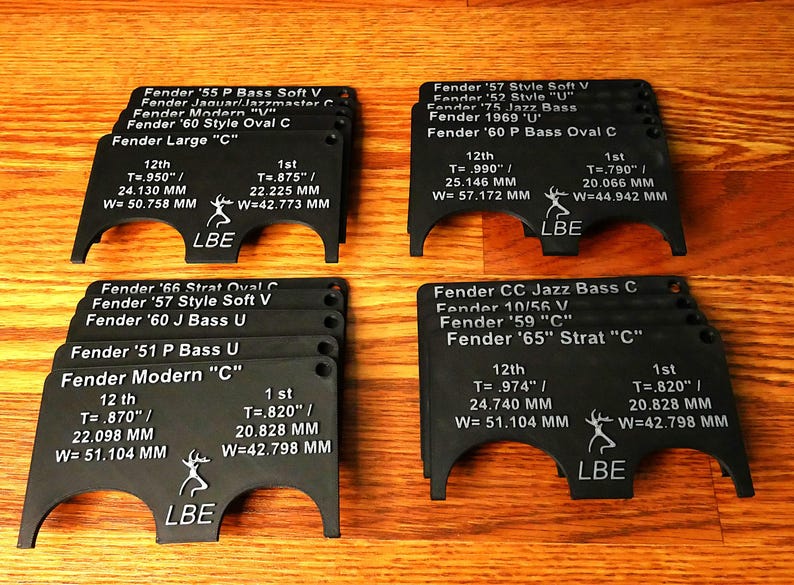 May include: A set of black plastic guitar nut templates for different Fender guitar models. Each template is labeled with the guitar model, year, and string measurements in inches and millimeters. The templates are arranged in two rows of five.