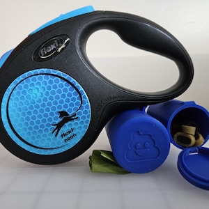 May include: Black and blue Flexi neon retractable dog lead with a matching blue waste bag dispenser. The lead has a black handle and a chrome-coloured metal clasp. The dispenser is filled with dog treats and waste bags.