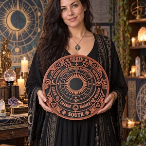 May include: A circular black and copper-colored Universal Pendulum Radionic Board featuring cardinal directions, percentage scales, and text including Yes, No, Recheck, Release, Balance, Charge, Clear, Maybe, and North, South, East, West.