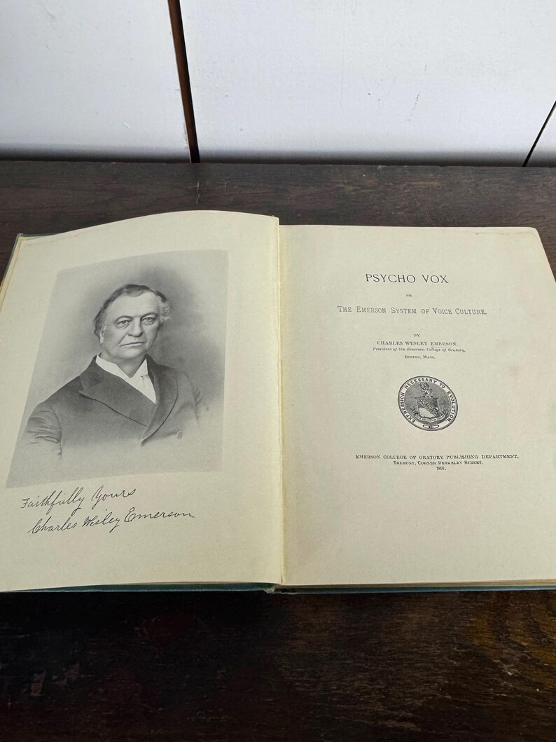 Puede incluir: Un retrato en blanco y negro de un hombre con bigote y barba. El hombre lleva un traje oscuro y una camisa blanca. La imagen es de un libro titulado "Psycho Vox: The Emerson System of Voice Culture" de Charles Wesley Emerson. El libro est&aacute; publicado por el Departamento de Publicaciones del Emerson College of Oratory.