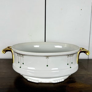 May include: White porcelain serving bowl with gold handles and green and gold geometric design.