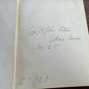 Puede incluir: Primer plano de la p&aacute;gina de inscripci&oacute;n de un libro con texto escrito a mano que dice "Cora St John Futch, Athens, Puria Nov. 12. 97 C. V. S. n. S."