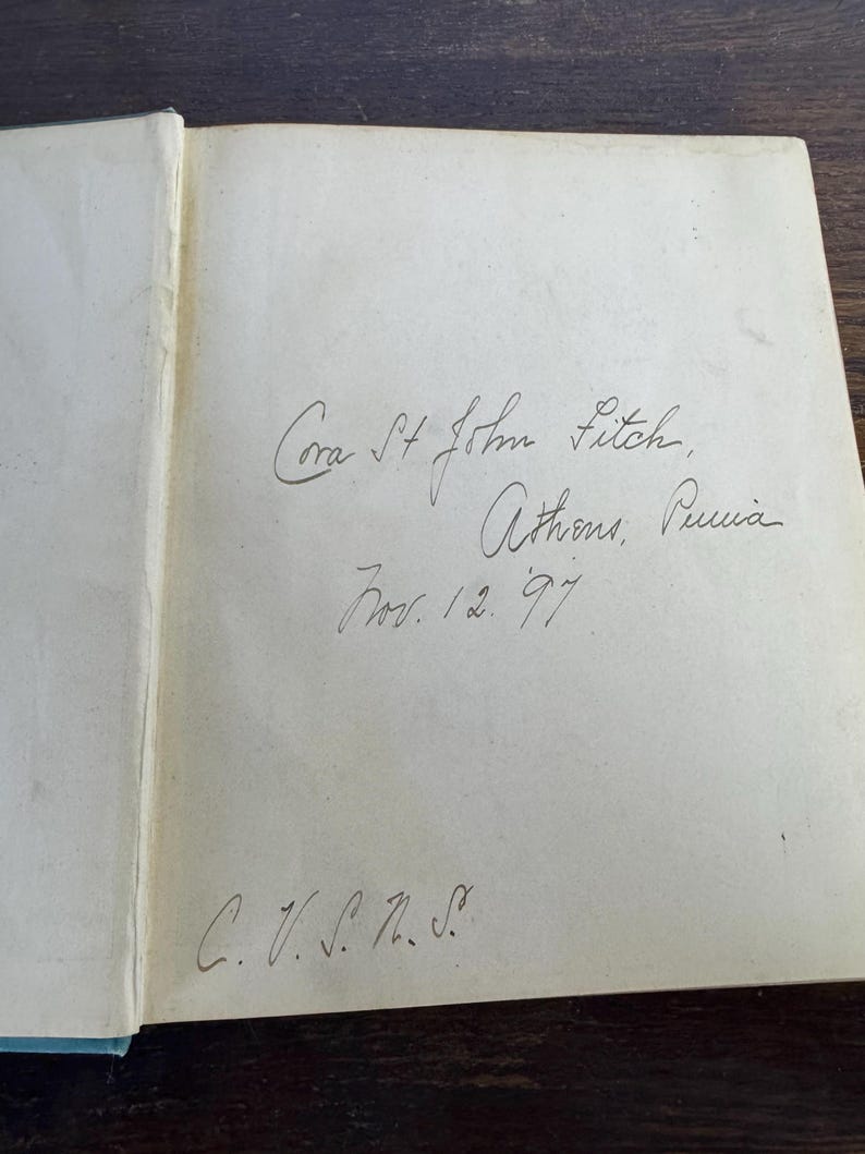 Puede incluir: Primer plano de la p&aacute;gina de inscripci&oacute;n de un libro con texto escrito a mano que dice "Cora St John Futch, Athens, Puria Nov. 12. 97 C. V. S. n. S."