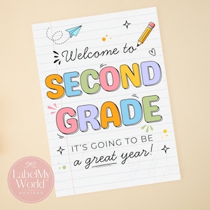 May include: A white paper sign with blue horizontal lines featuring the text Welcome to SECOND GRADE IT'S GOING TO BE a great year! The design includes a yellow pencil, a blue paper airplane, and colourful bubble letters in orange, blue, green, and pink.