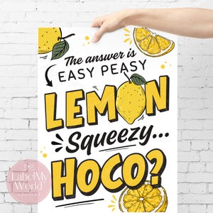 以下が含まれることがあります： 白いポスターに黄色の文字とレモンのイラスト。テキストは「The answer is EASY PEASY LEMON Squeezy... HOCO？」と書かれています。ポスターは人の手で持たれています。