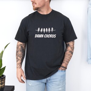 May include: A black t-shirt with a graphic of five birds on a wire and the text "DAWN CHORUS" printed in white.