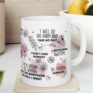 Puede incluir: Taza de caf&eacute; de cer&aacute;mica blanca con un fondo de acuarela rosa y blanco. La taza presenta texto negro con mensajes empoderadores, que incluyen "No har&eacute; da&ntilde;o y no aceptar&eacute; tonter&iacute;as", "Soy una mujer adulta y hago lo que quiero", "Soy incre&iacute;blemente genial", y "S&eacute; incre&iacute;blemente valiente".