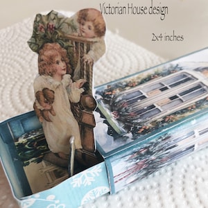 May include: A printable Christmas matchbox design featuring a Victorian house with a blue and white snowflake pattern on the bottom. The design is 2x4 inches.