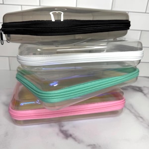 Astuccio rigido con cerniera: trasparente, verde acqua, rosa o nero.