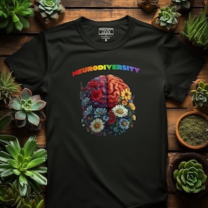 Könnte beinhalten: Schwarzes T-Shirt mit einem regenbogenfarbenen Gehirndesign mit Blumen. Der Text "Neurodiversity" ist über dem Gehirn gedruckt.