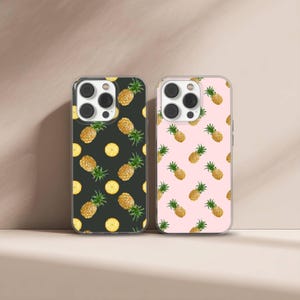 May include: Two phone cases with a repeating pineapple pattern. One case has a black background, the other is pink. The pineapples are yellow and green, with yellow pineapple slices scattered throughout.