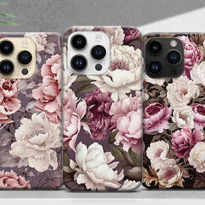 May include: Three iPhone cases with floral designs. The cases feature a pink, white, and purple floral pattern on a dark background. The cases are all the same size and shape.