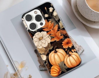 May include: A clear phone case featuring a fall-themed design. The case showcases pumpkins, orange leaves, and white flowers against a black background. The phone case is designed to fit a smartphone and has a camera cutout.