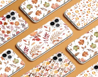 May include: A collection of clear smartphone cases featuring various watercolor patterns including autumn leaves, pumpkins, coffee cups, and small flowers. Each case has a cutout for a triple-lens camera system and a transparent protective shell.