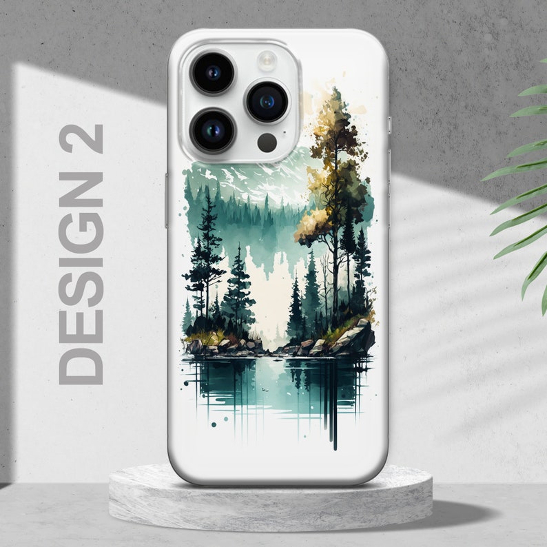 Puede incluir: Una funda de tel&eacute;fono blanca con un dise&ntilde;o de acuarela de una escena de bosque. La escena presenta un lago, &aacute;rboles y monta&ntilde;as en tonos verdes y azules.