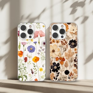 May include: Two clear phone cases with floral designs. The case on the left has a white background with colorful pressed flowers. The case on the right has a beige background with dried flowers in shades of brown and beige.