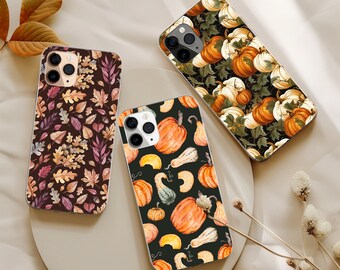 May include: Three smartphone cases featuring distinct patterns. One case displays a dark brown background with multicolored autumn leaves. Another case features a black background with orange pumpkins and gourds. The third case shows a black background with white and orange pumpkins.