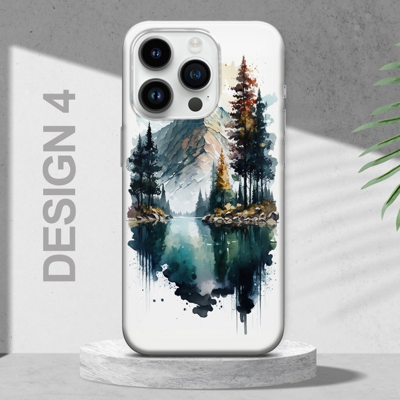 Puede incluir: Una funda de tel&eacute;fono blanca con un dise&ntilde;o de acuarela de un lago de monta&ntilde;a y &aacute;rboles. El dise&ntilde;o presenta un reflejo de los &aacute;rboles y las monta&ntilde;as en el agua.