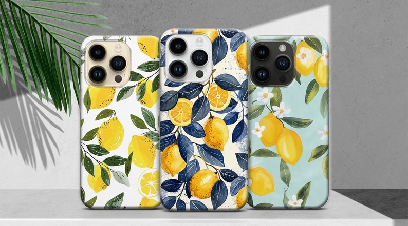 May include: Three iPhone cases with different lemon designs. The first case has a white background with yellow lemons and green leaves. The second case has a white background with blue leaves and yellow lemons. The third case has a light blue background with yellow lemons and white flowers.