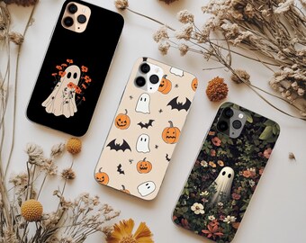 May include: Three smartphone cases featuring Halloween designs. One is black with a ghost holding orange flowers, one is cream with orange pumpkins, black bats, and white ghosts, and one features a ghost amidst a dense garden of colorful flowers.