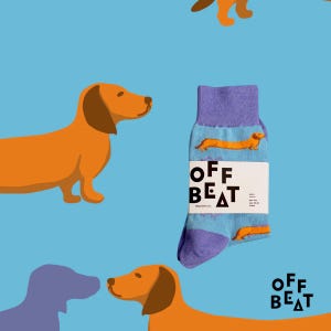 May include: A pair of purple and blue socks with a dachshund pattern. The socks have the text "OFF BEAT" on the side.