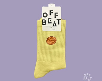 Op de afbeelding: Lichtgele sokken met een bruin hersenmotief. De sokken hebben een geribbelde textuur en een wit label met de tekst "OFF BEAT". Maat 41-46.