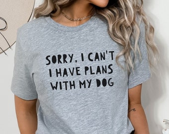 May include: Grey t-shirt with the text "Sorry, I can't I have plans with my dog" printed in black.