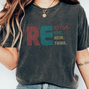 Könnte beinhalten: Ein dunkelgraues T-Shirt mit einer Grafik im Vintage-Stil, auf dem "RECYCLE. USE. NEW. THINK." steht.