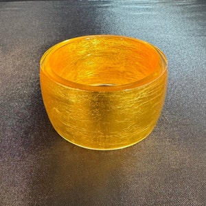 May include: A gold-colored bangle bracelet with a textured surface.