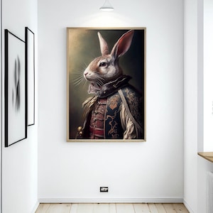 Pu&ograve; includere: Un dipinto incorniciato di un coniglio vestito con un costume dorato e rosso con un mantello di pelliccia marrone e bianco. Il coniglio sta guardando a sinistra dell'immagine.