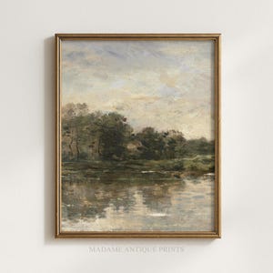 May include: A framed landscape painting featuring a calm body of water reflecting a cloudy sky and a line of dark green trees along the horizon. The artwork is enclosed in a thin, metallic gold frame and includes the text MADAME ANTIQUE PRINTS.