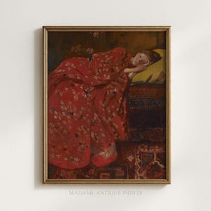 May include: Framed vintage art print featuring a woman in a red floral robe, resting on a bed with a yellow pillow. The artwork has a gold frame and is signed "MADAME ANTIQUE PRINTS" at the bottom.