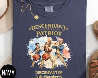 May include: Navy blue t-shirt with the text "DESCENDANT OF A PATRIOT" and an illustration of three men playing instruments. The shirt also includes the text "DESCENDANT OF Luke Stansberry 1758-1848 North Carolina."