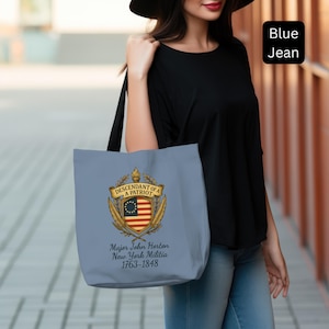 May include: A light blue tote bag featuring a patriotic emblem with the text "Descendant of a Patriot." The emblem includes a shield with the American flag, a banner, and the text "Major John Horton New York Militia 1763-1848."
