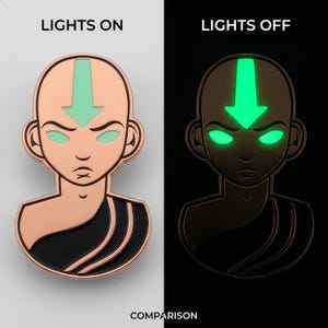 May include: A metal enamel pin featuring a stylized bust of a bald figure with a downward-pointing arrow on the forehead. The pin has rose gold metal outlines, black clothing details, and glow-in-the-dark light green arrow and eye accents.