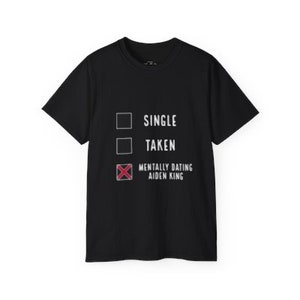 Puede incluir: Camiseta negra con un gráfico blanco que dice "Soltero, En Pareja, Mentalmente Saliendo con Aiden King" con una casilla de verificación junto a cada opción. La casilla junto a "Mentalmente Saliendo con Aiden King" está marcada con una X roja.