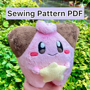 Könnte beinhalten: Ein rosa-brauner Plüschcharakter, der einen gelben Stern hält. Der Charakter hat große schwarze Augen, rote Wangen und einen lächelnden Mund. Der Text "Sewing Pattern PDF" wird über der Figur angezeigt.