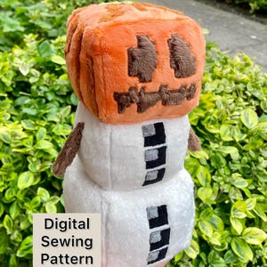 May include: A soft toy combining a pumpkin and a snowman. The orange pumpkin head has brown facial features. The snowman body is white with black and grey details. The text "Digital Sewing Pattern" is visible.
