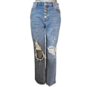 Könnte beinhalten: Hellblaue Jeans mit Knopfleiste und Distressed-Details. Die Jeans hat zerrissene Knie und eine verwaschene Waschung. Die Jeans ist gerade geschnitten.